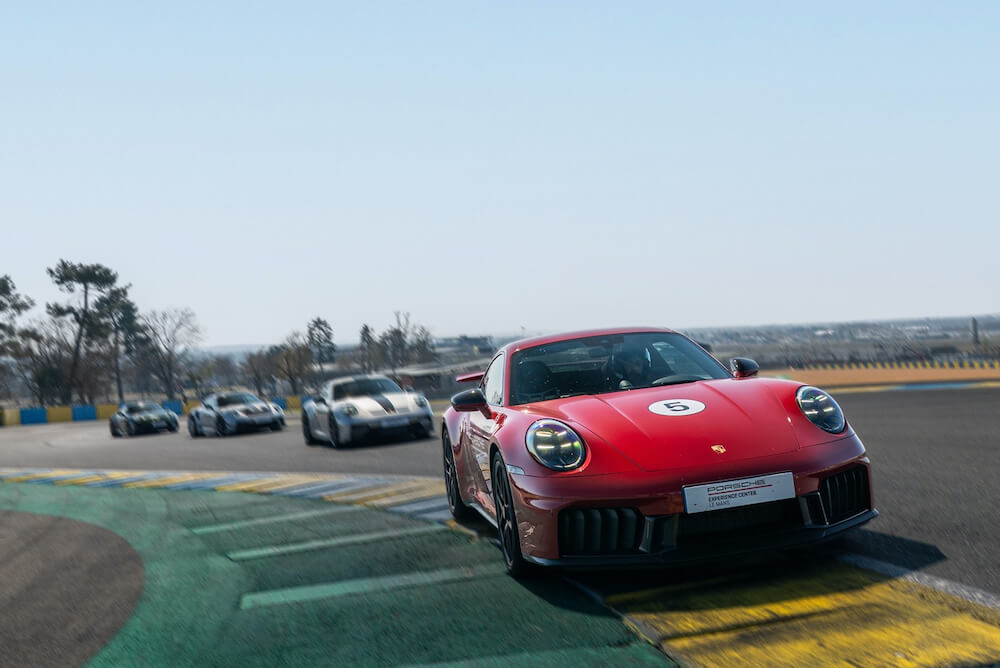 Porsche 911 GT3 rouge en action sur circuit avec plusieurs voitures en arrière plan