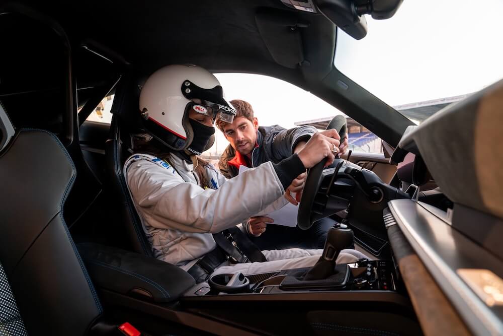 instructeur accompagnant un pilote dans une Porsche sur circuit